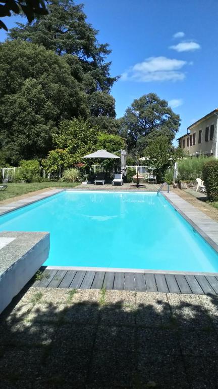 a large blue swimming pool with a wooden deck at Hôtel La Flambée in Bergerac