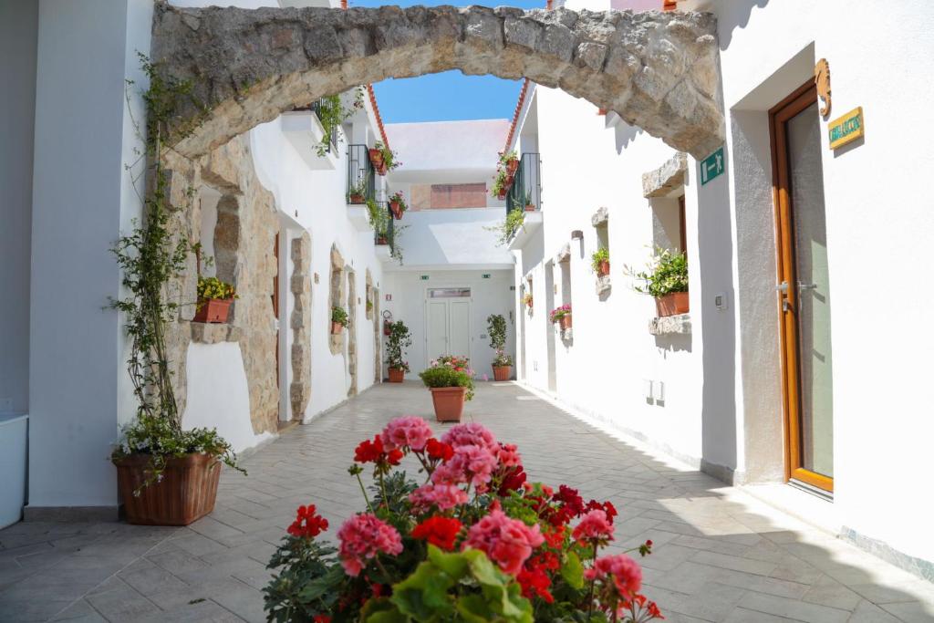 an archway in a white alley with flowers at Olbia Domus Inn in Olbia