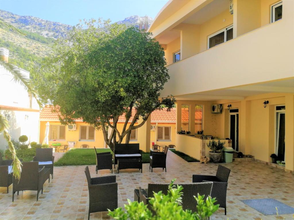 a patio with chairs and a tree in front of a building at Apartments Villa Jagoda in Sutomore