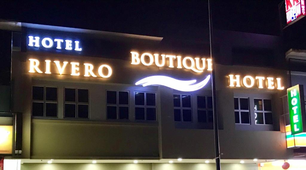 um hotel com sinais de néon na lateral de um edifício em RIVERO BOUTIQUE HOTEL Seremban 2 em Seremban