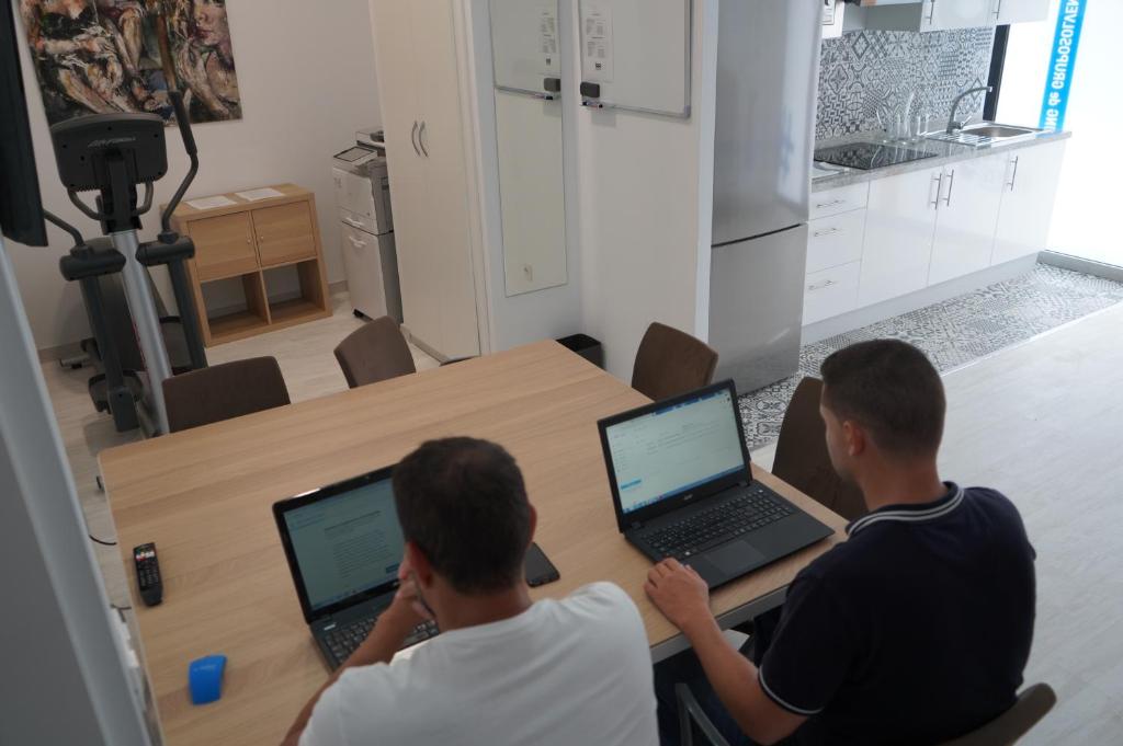 Coworking Studio في لاس بالماس دي غران كاناريا: يجلس رجلان على طاولة مع أجهزة اللاپتوپ الخاصة بهم