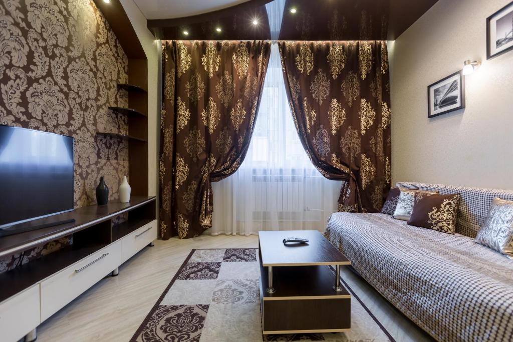 sala de estar con sofá y TV en Five Stars Center City, en Krasnoyarsk