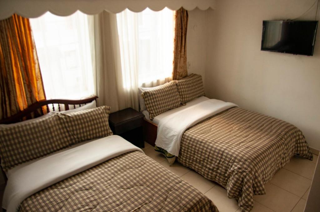 a hotel room with two beds and a tv at La Gran Fortaleza B&B in Bogotá