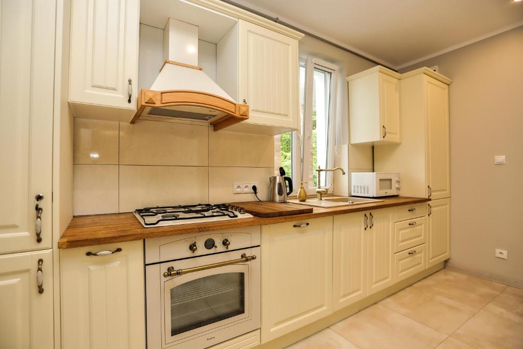 uma cozinha com armários brancos e um forno com placa de fogão em Apartament Diana em Karpacz