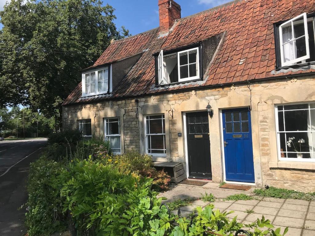 uma casa velha com uma porta azul numa rua em Ham Tree Cottage em Trowbridge