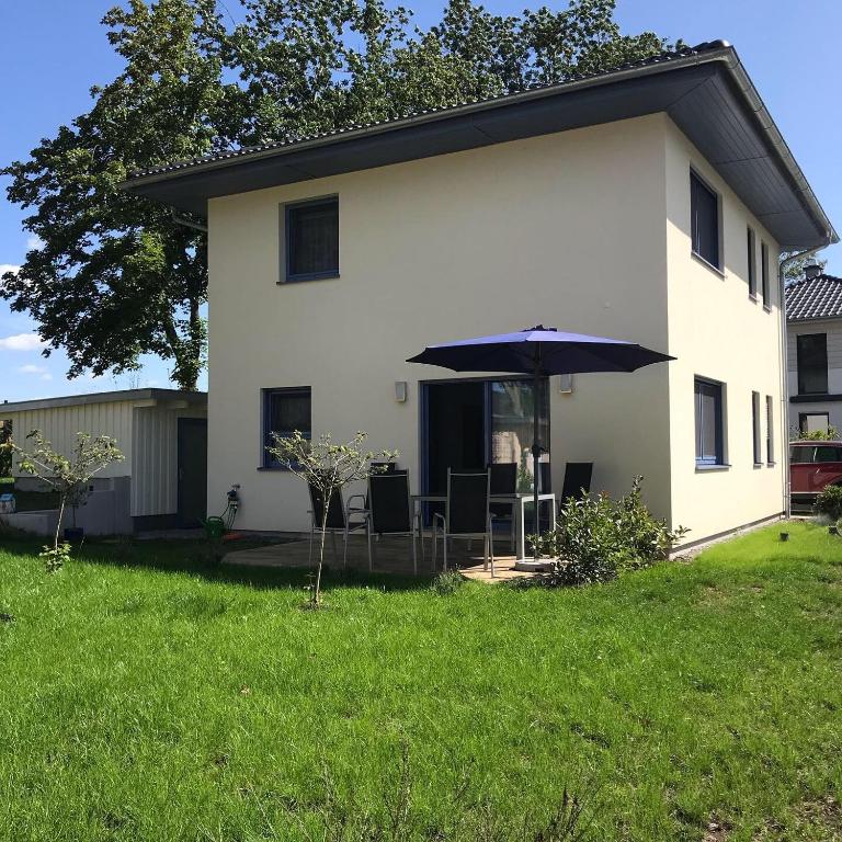 a white house with an umbrella in the yard at Haus Seewind Hohenfelden in Hohenfelden