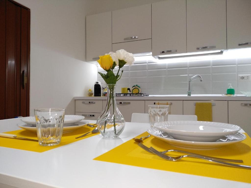 a kitchen with a table with plates and flowers in a vase at La Casa di Bianca in Caltagirone