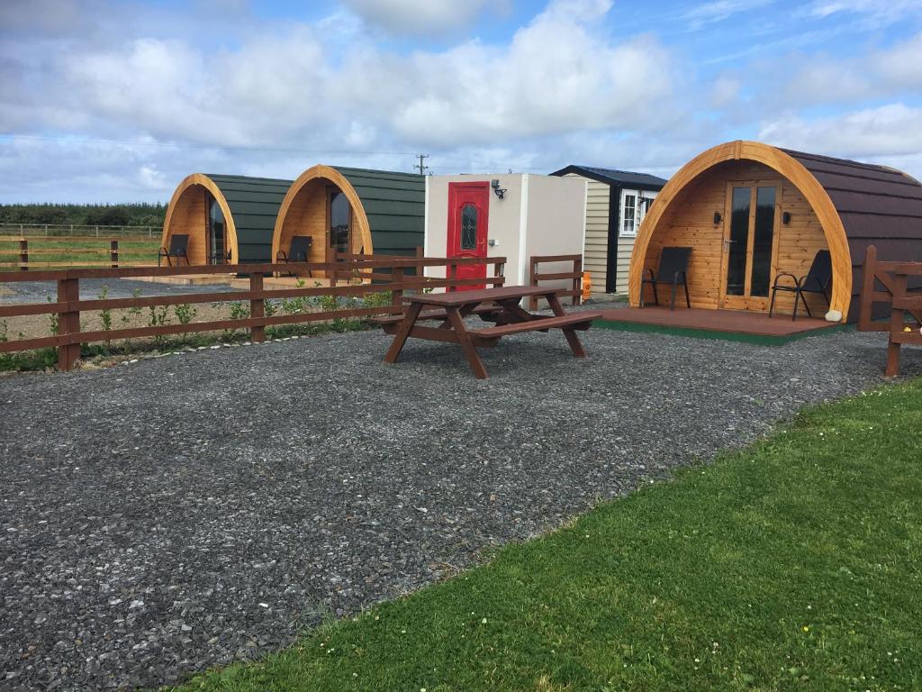 un grupo de cabañas con mesa de picnic y banco en Emlagh, Self Catering Glamping Pods, en Kilkee