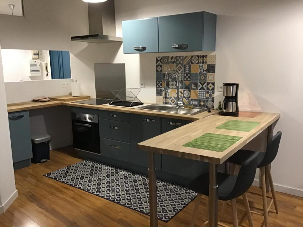 une cuisine avec des placards bleus et une table en bois dans l'établissement Appartement de 80m2 au cœur de Perpignan, à Perpignan