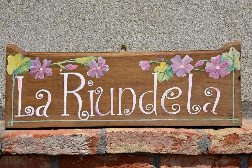 un panneau sur un mur de briques avec des fleurs sur lui dans l'établissement B&B La Riundela, à Asti