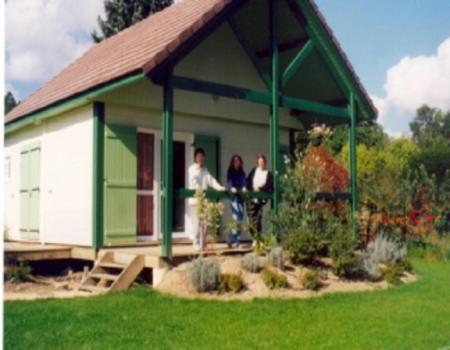 2 personnes debout sur la terrasse couverte d'une maison dans l'établissement Village-Chalets Le Rû du Pré, à Cravant