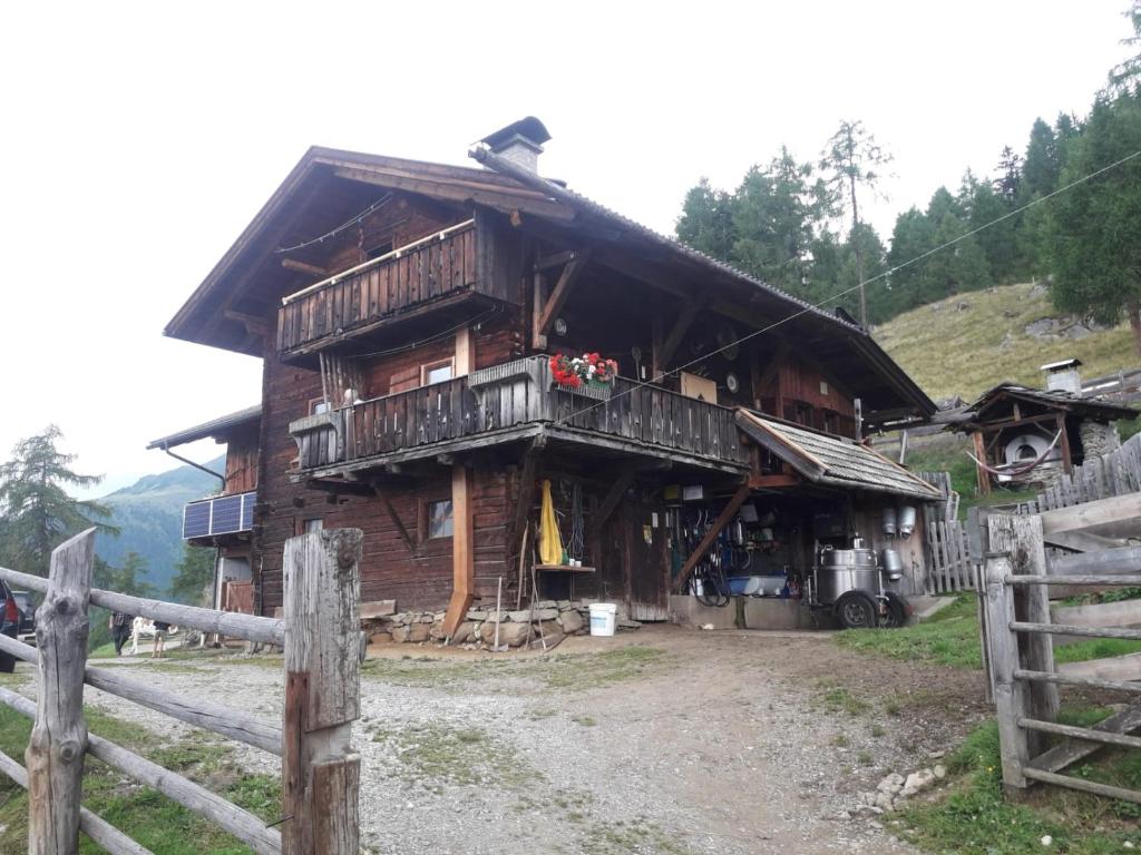 a wooden house with a balcony and a fence at Unterniggleralm in Thurn