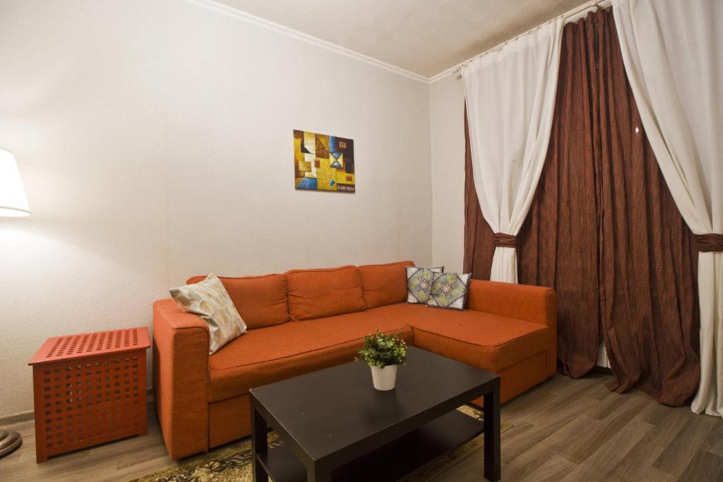 モスクワにあるLakshmi Apartment 3k Mayakovskayaのリビングルーム(窓の前にオレンジ色のソファ付)