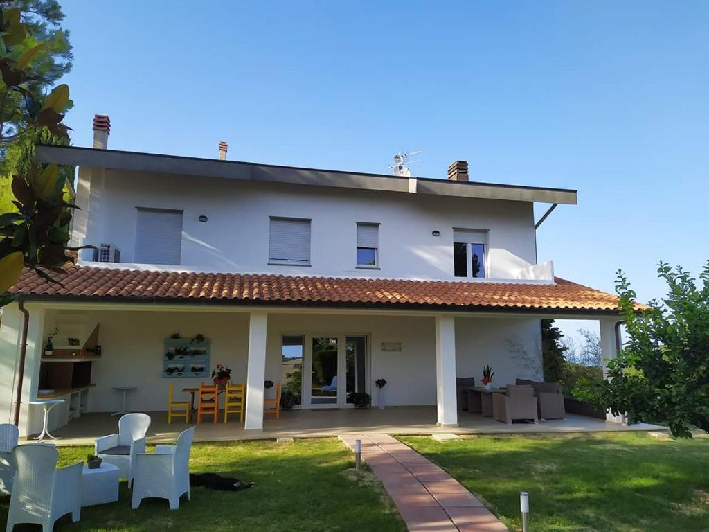 ein großes weißes Haus mit einer Terrasse und Stühlen in der Unterkunft Pizzacalla in Pineto