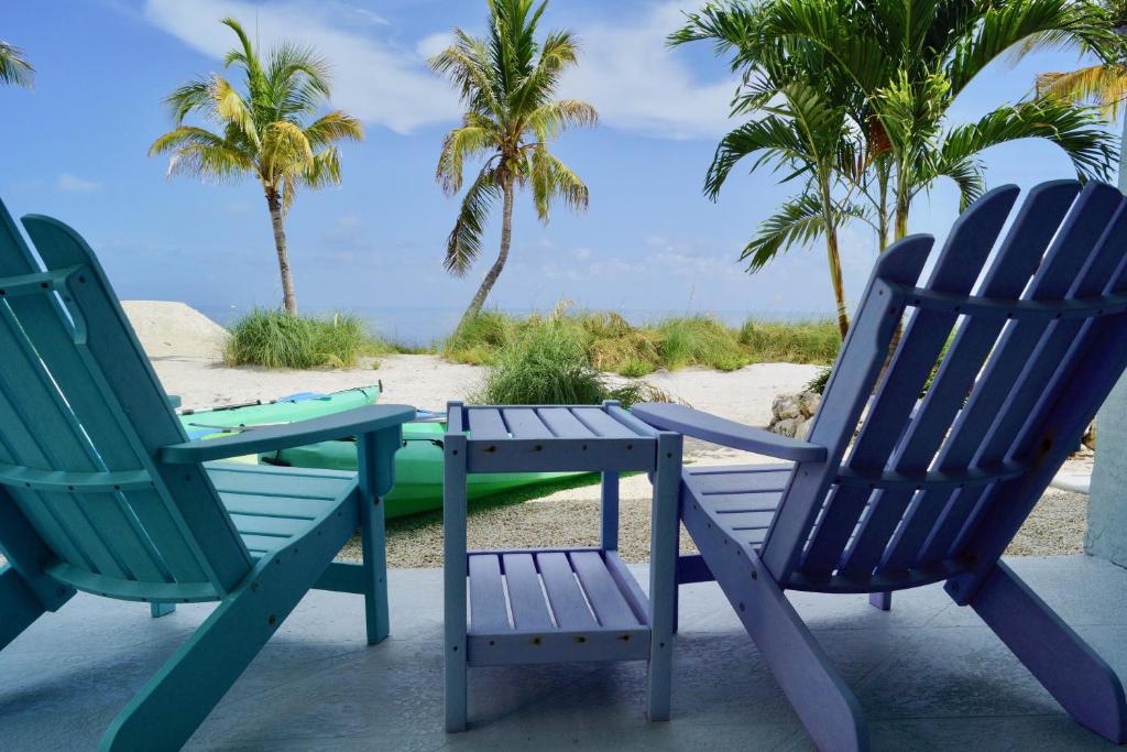 two chairs and a table on a beach with palm trees at Deer Run on the Atlantic in Big Pine Key