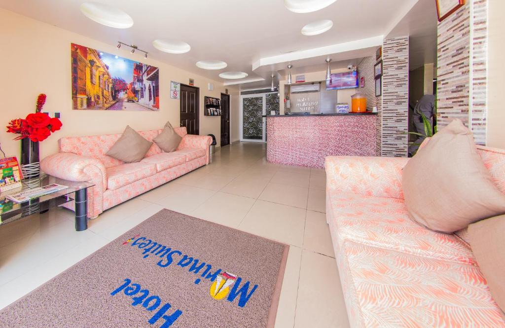 sala de estar con sofás rosados y cocina en Hotel Marina Suites By GEH Suites en Cartagena de Indias