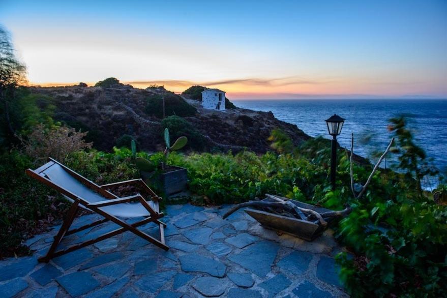 a chair sitting on a stone patio near the ocean at Niriides Studios in Armenistis