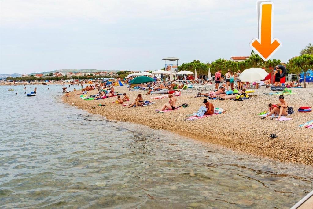 a group of people sitting on a beach at Apartment Nediljka in Vodice