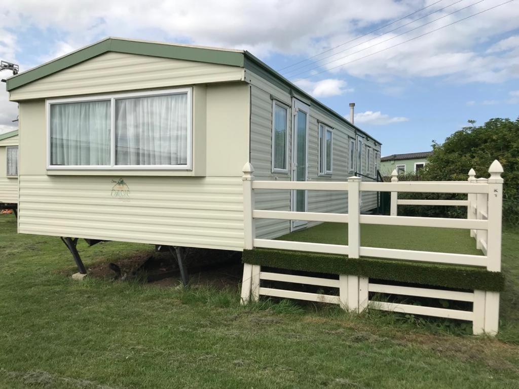 a tiny house with a white fence in a yard at 8 Berth Sunnymede (Atlas) in Ingoldmells