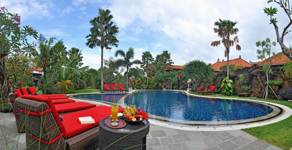 a swimming pool with red chairs and a red couch at Bali Aroma Exclusive Villas in Seminyak