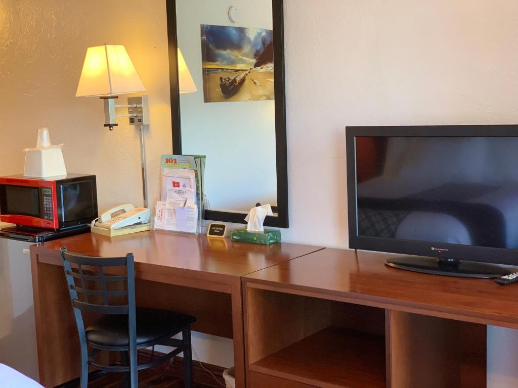 a desk in a hotel room with a television and a chair at Red Carpet Inn Medford in Medford