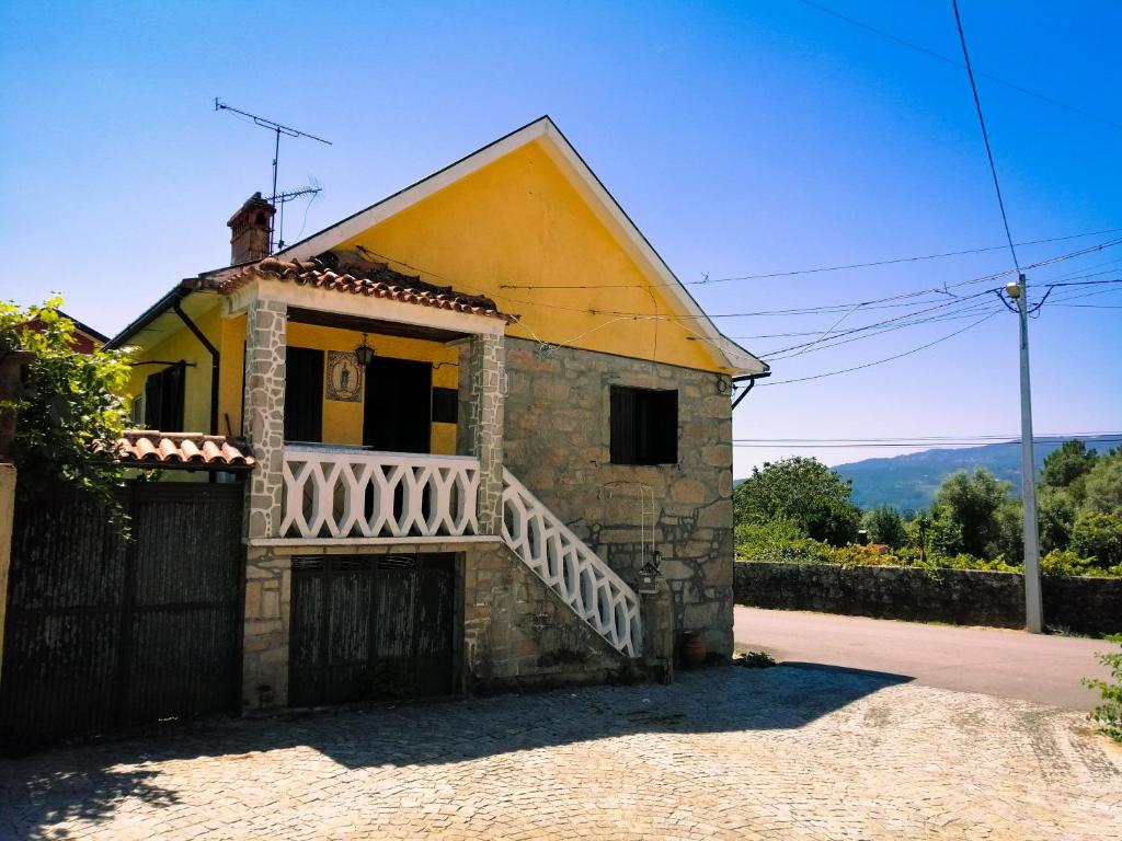 a small yellow house with a balcony on a street at Casa Glória in Ribeiradio
