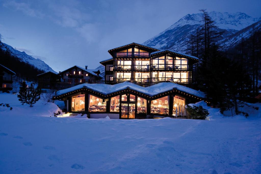 une grande maison dans la neige la nuit dans l'établissement Wellness Spa Pirmin Zurbriggen, à Saas-Almagell