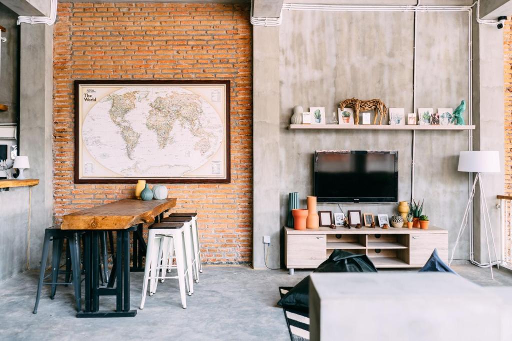 a room with a table and a television and a brick wall at SO! Boutique Hostel in Malang