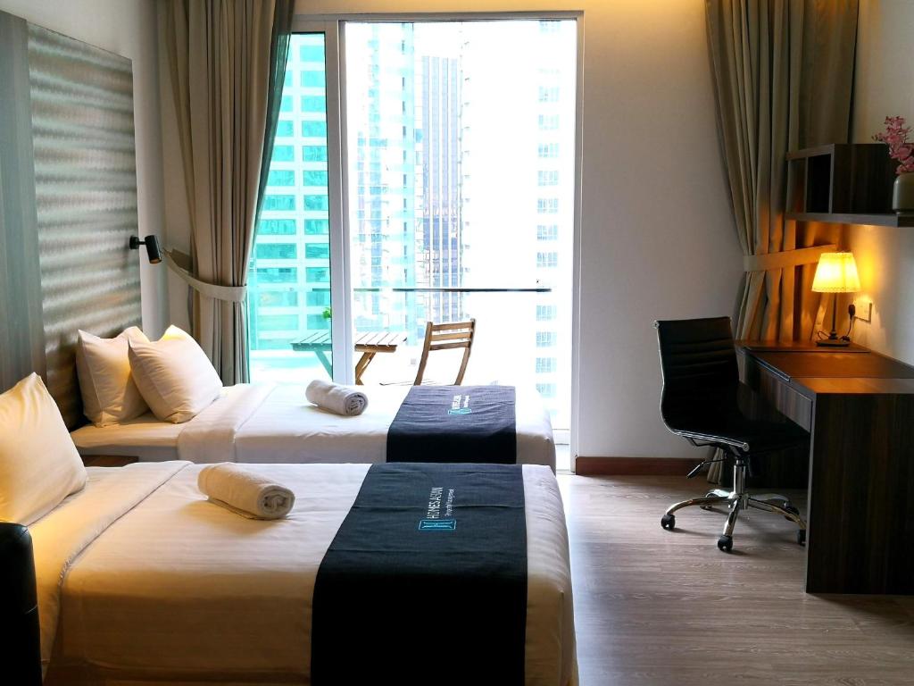 a hotel room with two beds and a desk at One Bukit Ceylon by Homes Asian in Kuala Lumpur