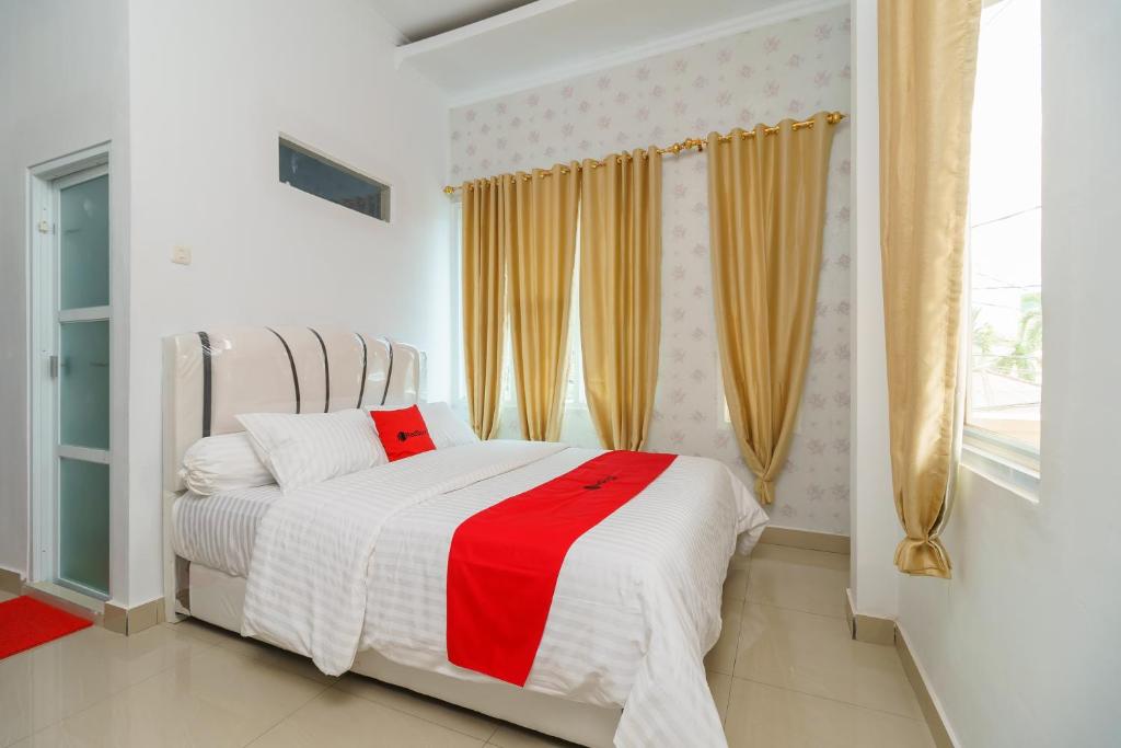 a bedroom with a bed with a red and white blanket at RedDoorz Syariah near Simpang Sekip Palembang in Palembang