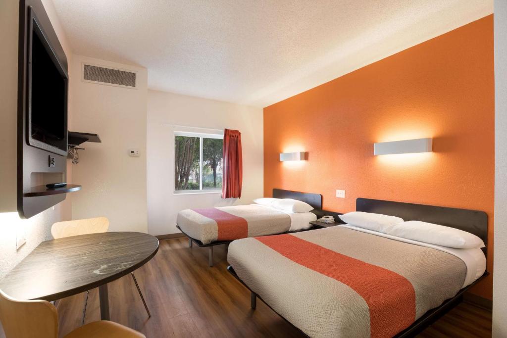 a hotel room with two beds and a table at Motel 6-Orlando, FL - International Dr in Orlando