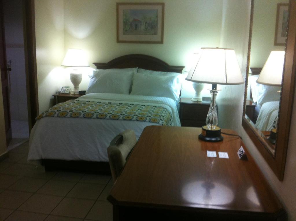 1 dormitorio con 1 cama, 2 lámparas y mesa en Micro Hotel Condo Suites, en Santo Domingo