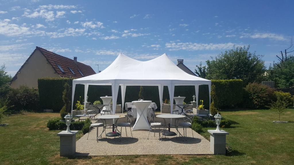 a white tent with tables and chairs in a yard at La Clef Dort in Beauchamps