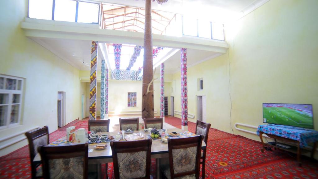 a dining room with a table and chairs and a television at Qutlug Qadam Guest House in Khiva