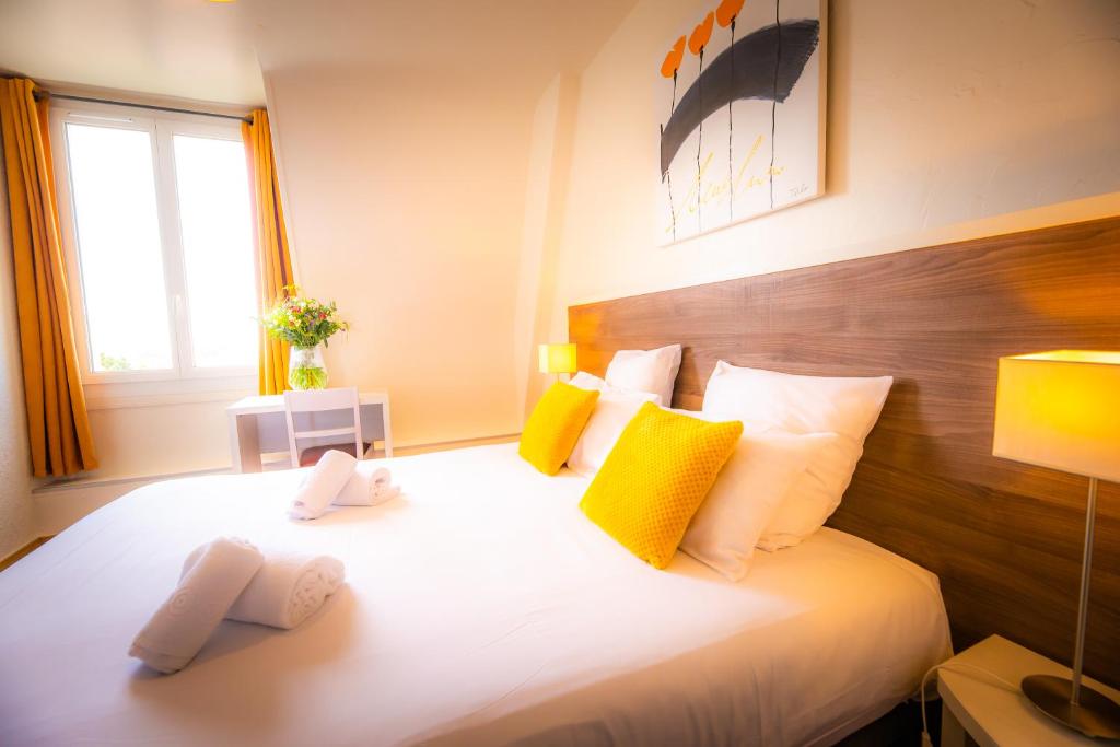 a bedroom with a large bed with yellow and white pillows at La Villa Andry in Ouistreham