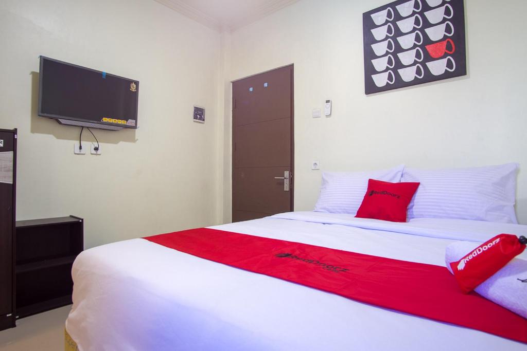 een slaapkamer met een groot wit bed met rode kussens bij RedDoorz near Taman Kota Ternate in Ternate