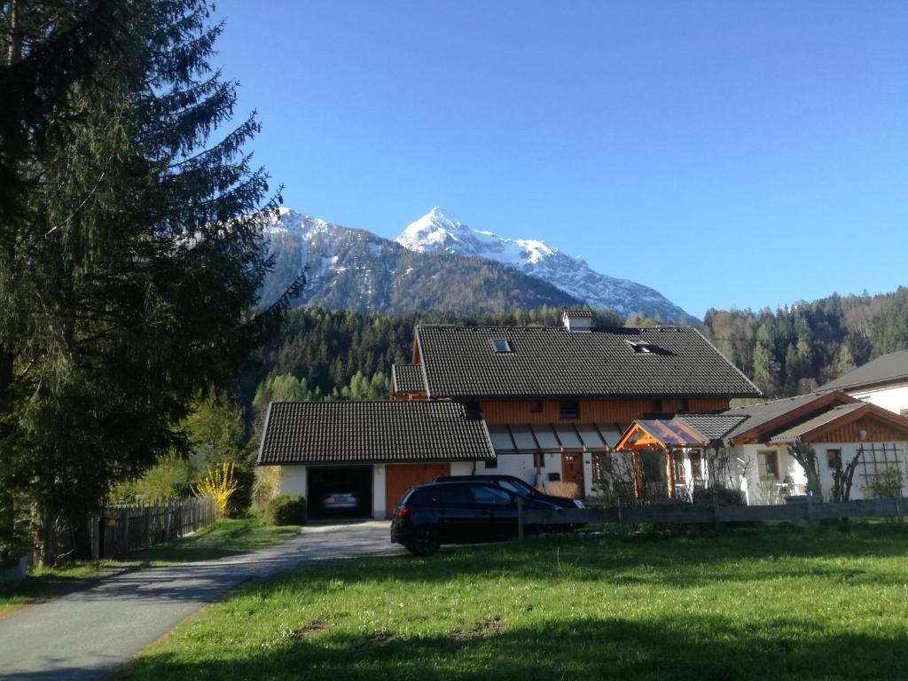une maison avec une voiture garée devant elle avec une montagne dans l'établissement Haus der Sonne, à Kötschach-Mauthen