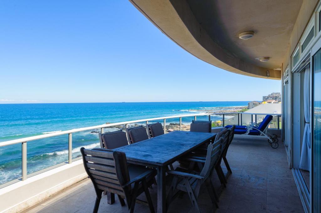 einen Tisch und Stühle auf einem Balkon mit Meerblick in der Unterkunft Ballito Manor Beach 405 - FAMILY ONLY - With Generator in Ballito