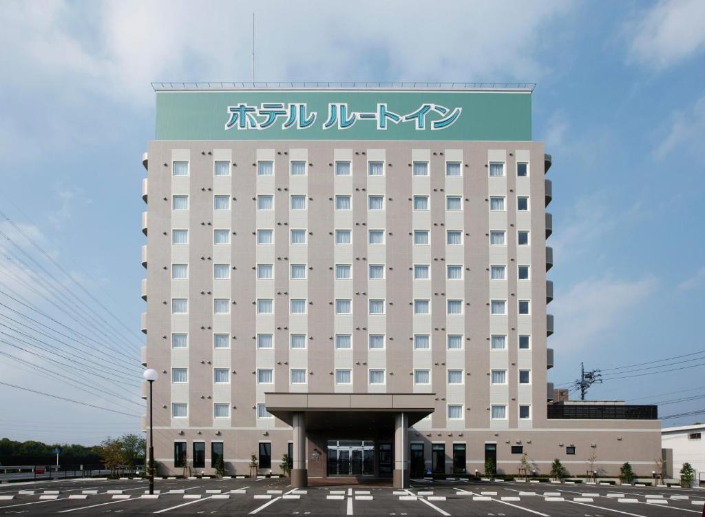 un gran edificio blanco con un cartel. en Hotel Route-Inn Handakamezaki, en Handa