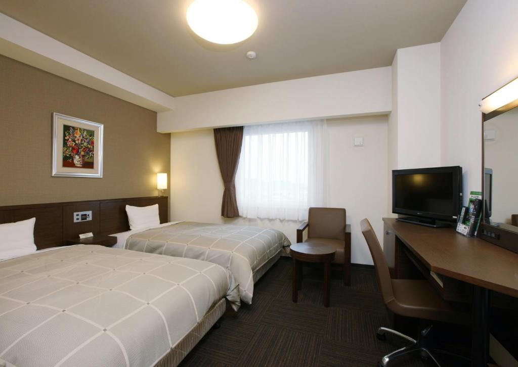 半田市にあるホテルルートイン半田亀崎のベッド2台とデスクが備わるホテルルームです。