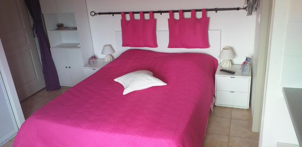 a bedroom with a pink bed with a white pillow at Chambre du Raisin in Puyricard