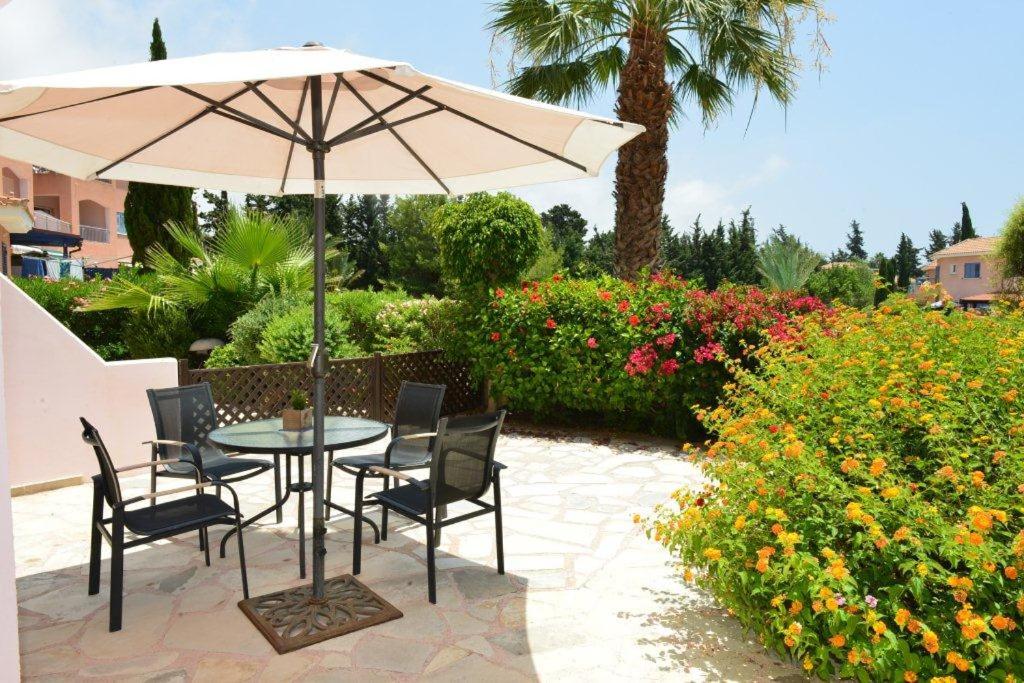Una mesa y sillas con una sombrilla en un patio. en Limnaria Villas Sunny Garden Apartment, en Pafos
