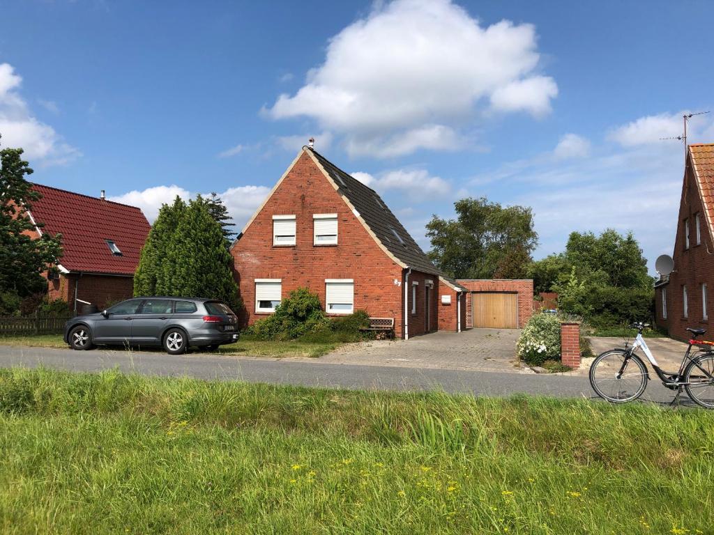 a house with a car parked in front of it at Ferienhaus Nordseerobbe in Friedrichskoog