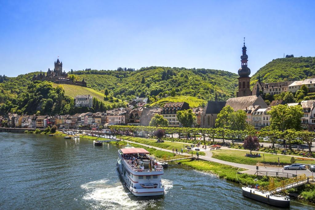 a boat traveling down a river in a city at MoselUnion - "schlafen & genießen" in Cochem