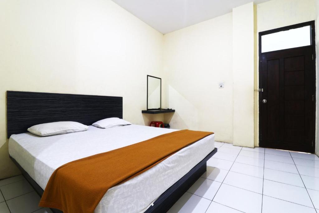 1 dormitorio con 1 cama grande y puerta negra en Guest House Taman Sari Syariah en Parit