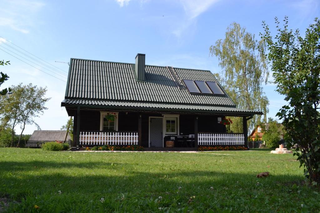 una casa con techo negro en un campo verde en Merkiokrantas Pirkia kaime, en Puvočiai
