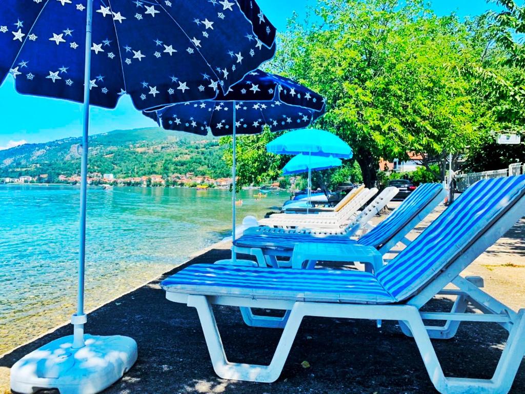 a group of chairs and umbrellas on a beach at Villa Boris- Next to the Beach with Parking in Ohrid