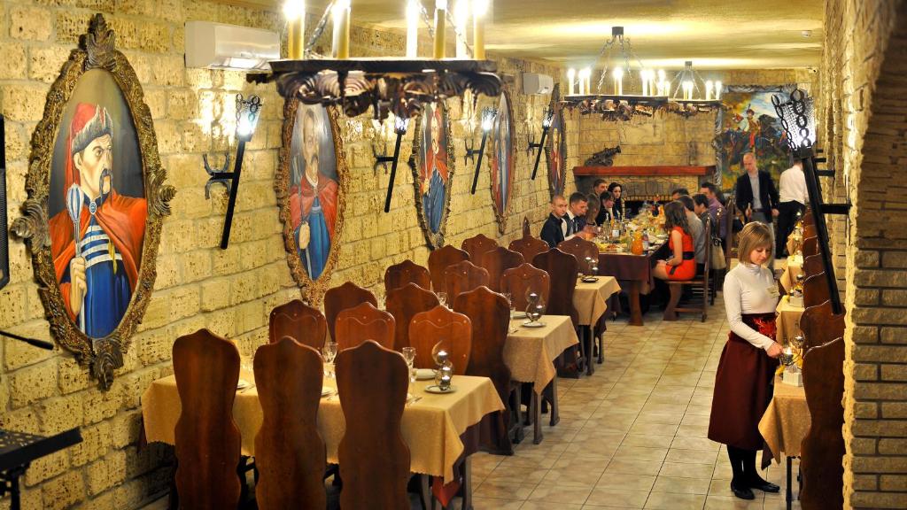 a restaurant with tables and chairs and people in a room at Готельно-ресторанний комплекс «Галицький замок» in Ternopilʼ