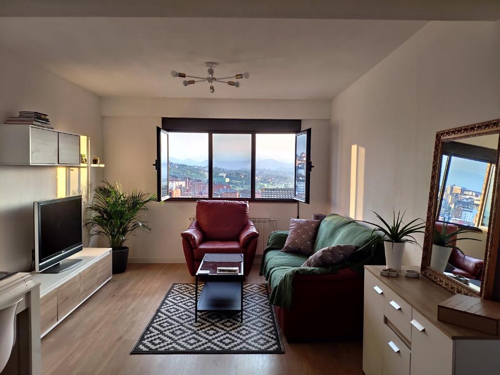 a living room with a couch and a tv at Apartamento LOS VEGA- parking privado in Oviedo
