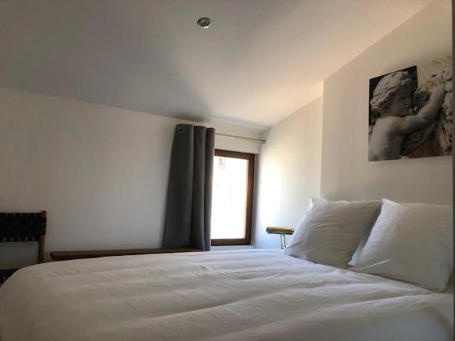 Schlafzimmer mit einem weißen Bett und einem Fenster in der Unterkunft Appartement avec terrasse panoramique au coeur de Nîmes in Nîmes